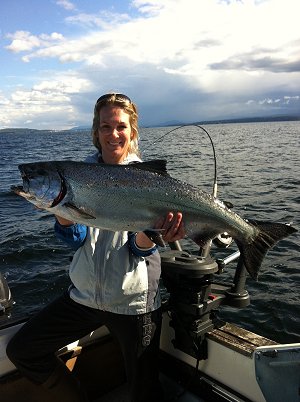Julia   with a nice 28 pound Chinook.  This salmon was landed using a green spatterback.  Julia was fishing with family and guided by guide Chad